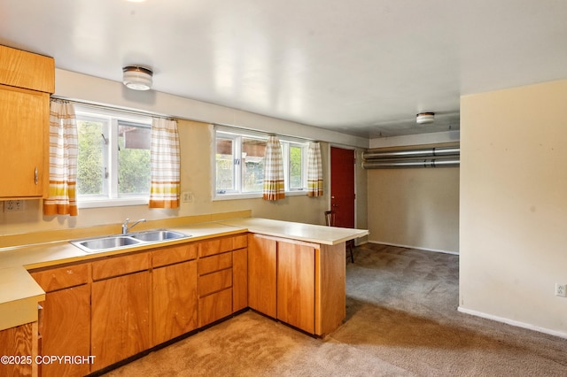 7101 Omalley Rd, Anchorage, AK 99507 - kitchen with a sink, light colored carpet, a peninsula, light countertops, and brown cabinetry