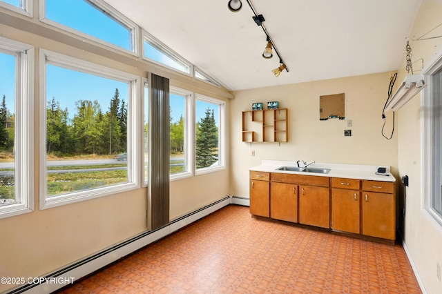 7101 Omalley Rd, Anchorage, AK 99507 - kitchen with a baseboard radiator, a sink, vaulted ceiling, brown cabinetry, and light countertops
