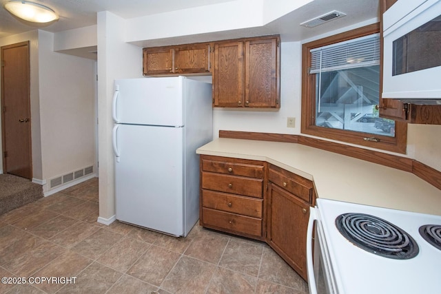 4063 E 20th Ave Unit D54, Anchorage, AK 99508 - kitchen with white appliances, light countertops, brown cabinetry, and baseboards