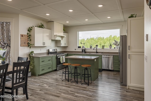 5233 W Jaxton Cir, Wasilla, AK 99623 - kitchen with green cabinets, stainless steel appliances, a breakfast bar area, a center island, and dark wood finished floors