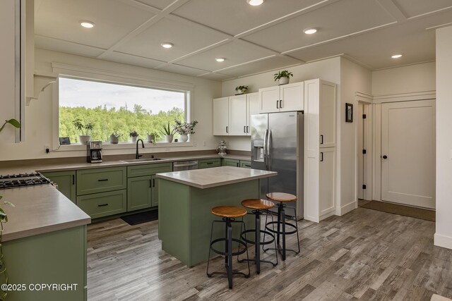 5233 W Jaxton Cir, Wasilla, AK 99623 - kitchen featuring green cabinets, appliances with stainless steel finishes, a sink, a kitchen breakfast bar, and wood finished floors