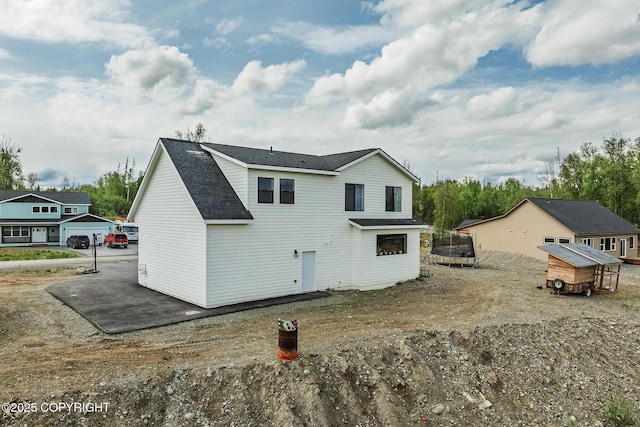 5233 W Jaxton Cir, Wasilla, AK 99623 - rear view of property featuring a trampoline, an outbuilding, roof with shingles, and exterior structure