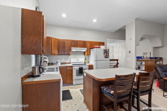 3529 W 41st Ave, Anchorage, AK 99517 - kitchen featuring white appliances, under cabinet range hood, light countertops, a sink, and a breakfast bar