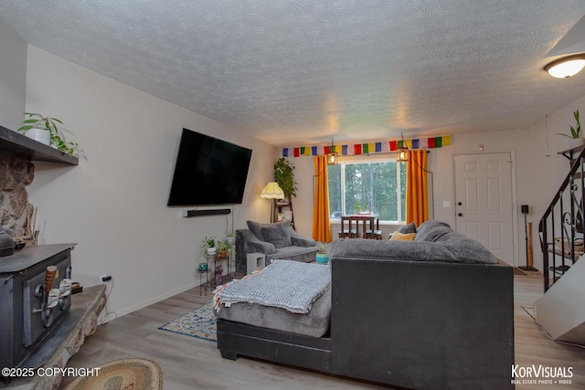 767 N Yakima St, Wasilla, AK 99654 - living room with light wood-type flooring, a textured ceiling, a wood stove, and stairway