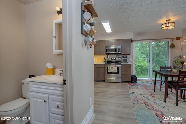 767 N Yakima St, Wasilla, AK 99654 - kitchen with appliances with stainless steel finishes, a textured ceiling, light wood-style floors, and light countertops
