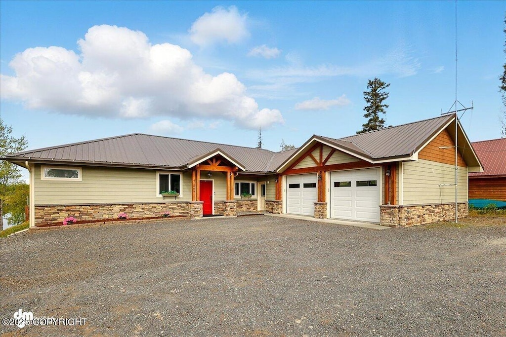 41609 E Lake Ave, Soldotna, AK 99669 - view of front of home with stone siding, a garage, metal roof, and gravel driveway