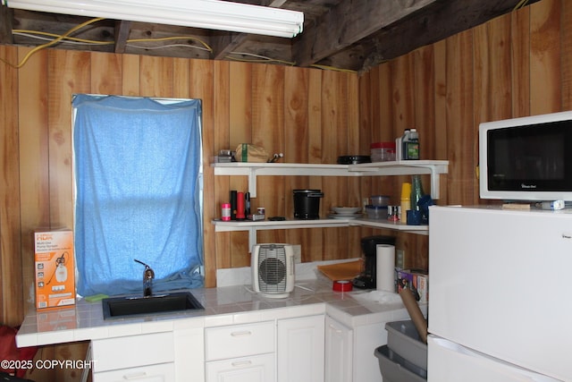 63760 Elizabeth Ave, Ninilchik, AK 99639 - kitchen with freestanding refrigerator, a sink, tile countertops, white cabinetry, and wooden walls