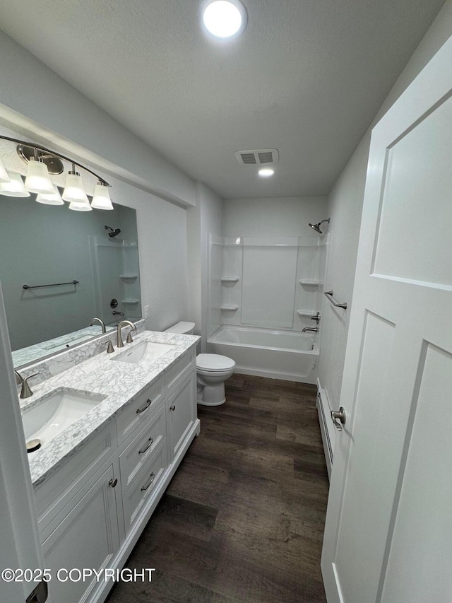 1430 Bridgeway St # 3, Anchorage, AK 99501 - bathroom with double vanity, toilet, a baseboard radiator, wood finished floors, and tub / shower combination