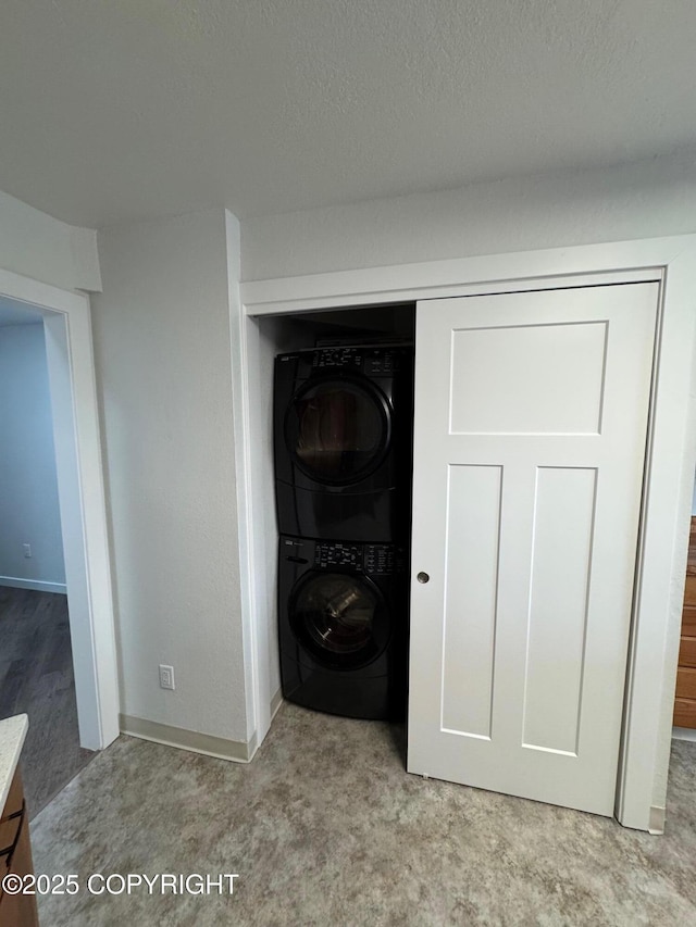 1430 Bridgeway St # 3, Anchorage, AK 99501 - detailed view of stacked washer / drying machine, baseboards, and a textured ceiling