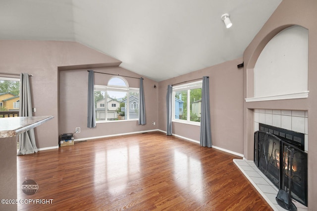 3933 Sycamore Loop, Anchorage, AK 99504 - unfurnished living room with lofted ceiling, a fireplace, wood finished floors, and baseboards