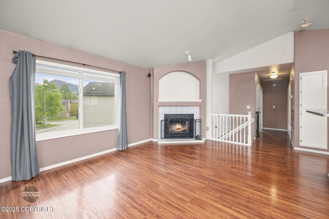 3933 Sycamore Loop, Anchorage, AK 99504 - unfurnished living room featuring wood finished floors, baseboards, vaulted ceiling, and a tiled fireplace