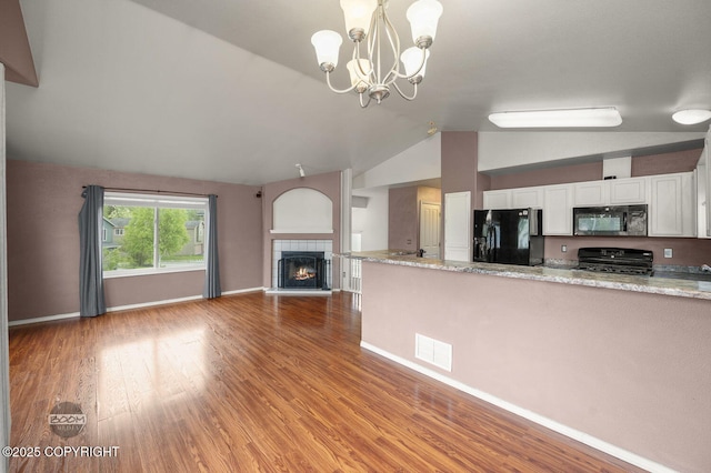 3933 Sycamore Loop, Anchorage, AK 99504 - kitchen with black appliances, vaulted ceiling, white cabinets, open floor plan, and light wood-style floors