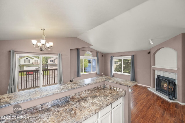 3933 Sycamore Loop, Anchorage, AK 99504 - kitchen featuring lofted ceiling, dark wood-style flooring, a tiled fireplace, a chandelier, and pendant lighting
