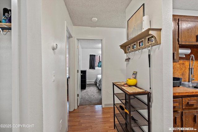 4433 San Ernesto Ave # 104, Anchorage, AK 99508 - hallway featuring wood finished floors, a textured ceiling, and a baseboard heating unit
