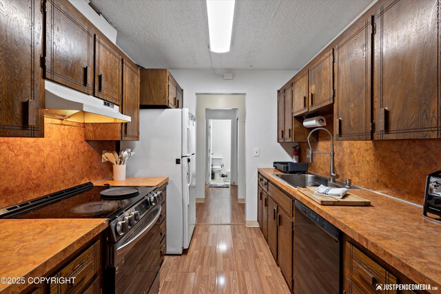 4433 San Ernesto Ave # 104, Anchorage, AK 99508 - kitchen featuring range with electric stovetop, black dishwasher, under cabinet range hood, a sink, and a textured ceiling