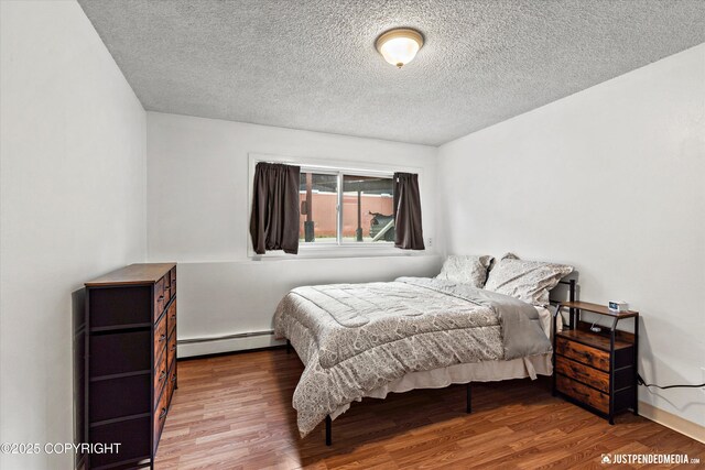 4433 San Ernesto Ave # 104, Anchorage, AK 99508 - bedroom with a baseboard heating unit, wood finished floors, and a textured ceiling