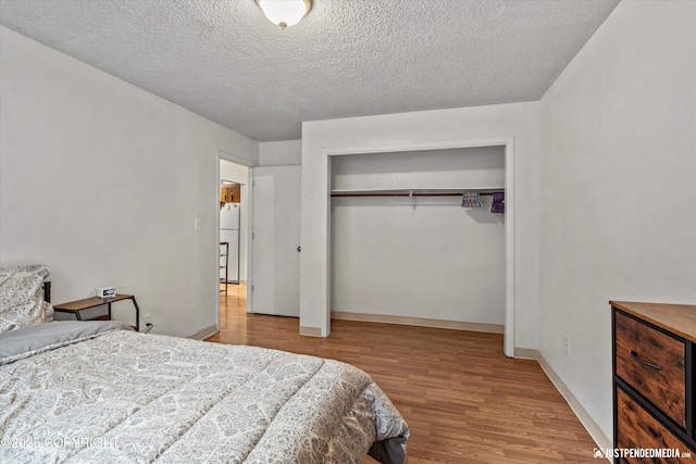 4433 San Ernesto Ave # 104, Anchorage, AK 99508 - bedroom featuring freestanding refrigerator, wood finished floors, a closet, a textured ceiling, and baseboards