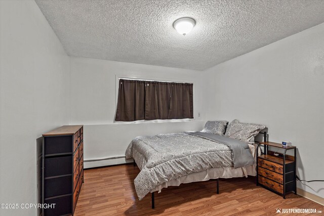 4433 San Ernesto Ave # 104, Anchorage, AK 99508 - bedroom with baseboard heating, wood finished floors, and a textured ceiling