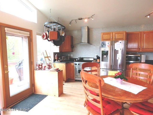 4259 Shirley Ct, Homer, AK 99603 - kitchen featuring stainless steel appliances, wall chimney exhaust hood, dark countertops, track lighting, and brown cabinets