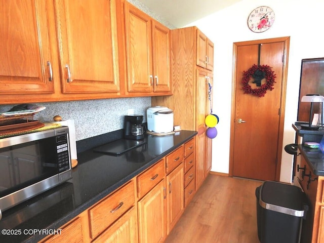 4259 Shirley Ct, Homer, AK 99603 - kitchen with stainless steel microwave, light wood-style floors, brown cabinets, and dark countertops