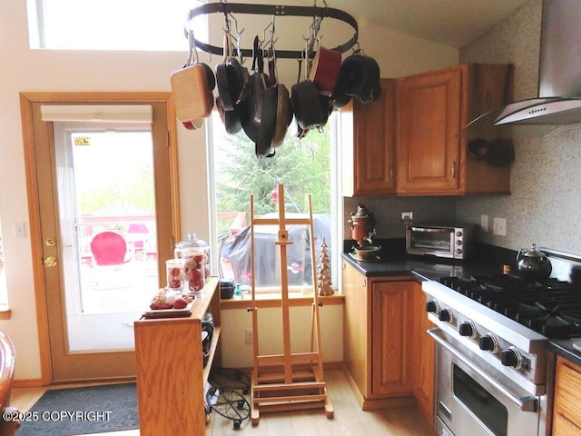 4259 Shirley Ct, Homer, AK 99603 - kitchen featuring high end stainless steel range, dark countertops, brown cabinets, and wall chimney range hood