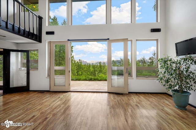 4821 S Outrigger Dr, Wasilla, AK 99654 - unfurnished living room featuring a towering ceiling, wood finished floors, healthy amount of natural light, and french doors