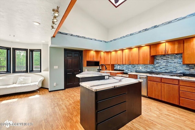 4821 S Outrigger Dr, Wasilla, AK 99654 - kitchen with a kitchen island with sink, light wood-type flooring, tasteful backsplash, a sink, and brown cabinetry