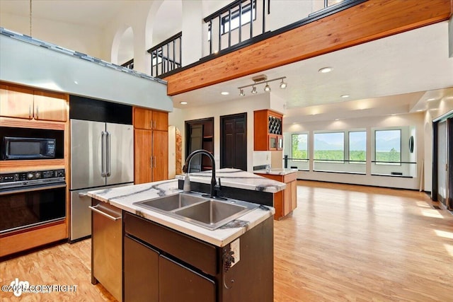 4821 S Outrigger Dr, Wasilla, AK 99654 - kitchen featuring black appliances, a sink, an island with sink, light wood-style floors, and light countertops