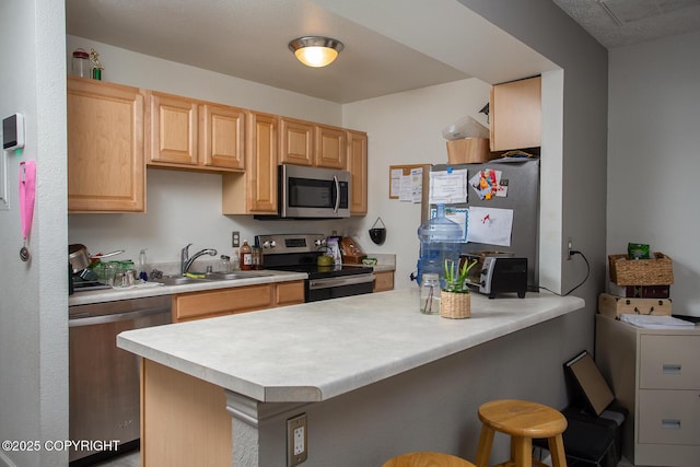 1701 Russian Jack Dr # D3, Anchorage, AK 99508 - kitchen featuring appliances with stainless steel finishes, a sink, a peninsula, a breakfast bar, and light countertops