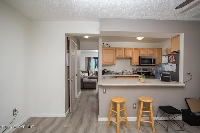1701 Russian Jack Dr # D3, Anchorage, AK 99508 - kitchen featuring stainless steel appliances, light countertops, light wood finished floors, light brown cabinets, and a sink