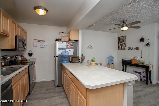 1701 Russian Jack Dr # D3, Anchorage, AK 99508 - kitchen with stainless steel appliances, a peninsula, ceiling fan, and light wood-style flooring