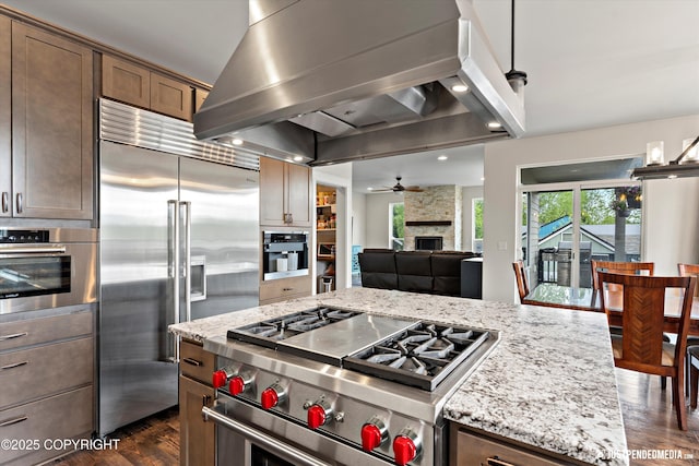 1506 M St, Anchorage, AK 99501 - kitchen featuring high quality appliances, wall chimney range hood, dark wood finished floors, a fireplace, and a ceiling fan
