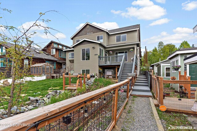 1506 M St, Anchorage, AK 99501 - rear view of house featuring stairway, a wooden deck, and a lawn