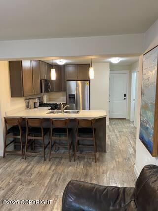 1506 M St, Anchorage, AK 99501 - kitchen with appliances with stainless steel finishes, light wood finished floors, a peninsula, a breakfast bar area, and a sink