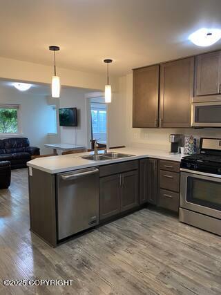 1506 M St, Anchorage, AK 99501 - kitchen featuring appliances with stainless steel finishes, a sink, a peninsula, light wood-style floors, and light countertops