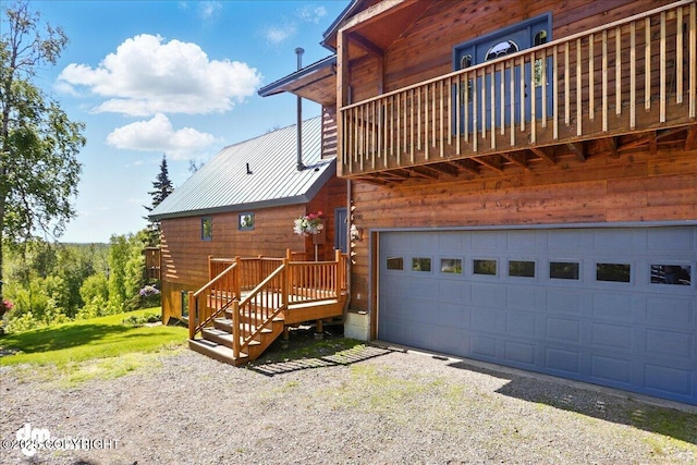 5680 W Birch Harbor Dr, Wasilla, AK 99623 - rear view of house featuring an attached garage, gravel driveway, metal roof, and a balcony