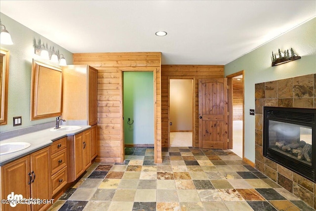 5680 W Birch Harbor Dr, Wasilla, AK 99623 - full bathroom with stone finish floors, double vanity, a tiled fireplace, wooden walls, and recessed lighting