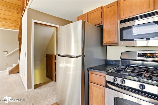 5680 W Birch Harbor Dr, Wasilla, AK 99623 - kitchen with stainless steel appliances, light colored carpet, dark countertops, brown cabinets, and baseboards
