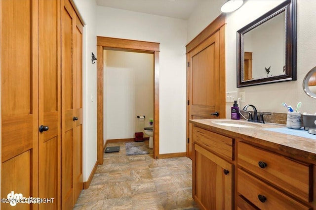 6325 S Hayfield Rd, Wasilla, AK 99654 - bathroom featuring vanity, stone finish flooring, toilet, and baseboards