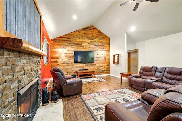 6325 S Hayfield Rd, Wasilla, AK 99654 - living area featuring a ceiling fan, wood walls, a stone fireplace, high vaulted ceiling, and baseboards
