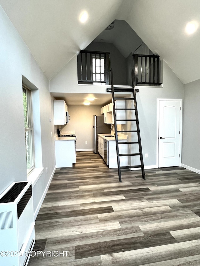 8201 W Teal Cir, Wasilla, AK 99623 - unfurnished living room with baseboards, dark wood finished floors, healthy amount of natural light, high vaulted ceiling, and a sink