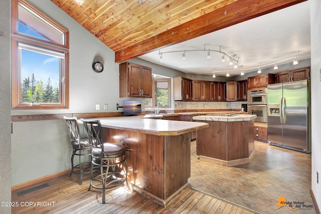 15245 Longbow Dr, Anchorage, AK 99516 - kitchen featuring appliances with stainless steel finishes, light countertops, light wood-type flooring, a peninsula, and a sink