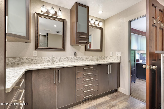 15245 Longbow Dr, Anchorage, AK 99516 - bathroom with double vanity, wood finished floors, a textured wall, and baseboards