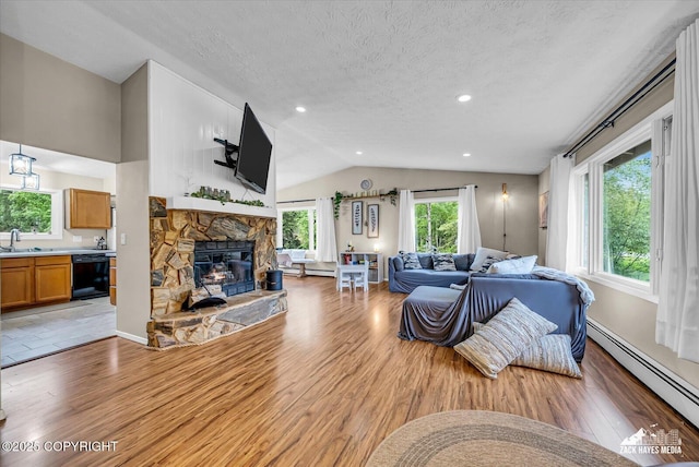 19705 Citation Rd, Eagle River, AK 99577 - living room featuring a baseboard heating unit, light wood finished floors, a fireplace, a textured ceiling, and vaulted ceiling