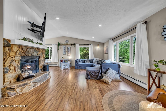 19705 Citation Rd, Eagle River, AK 99577 - living room featuring baseboard heating, wood finished floors, vaulted ceiling, a stone fireplace, and a textured ceiling