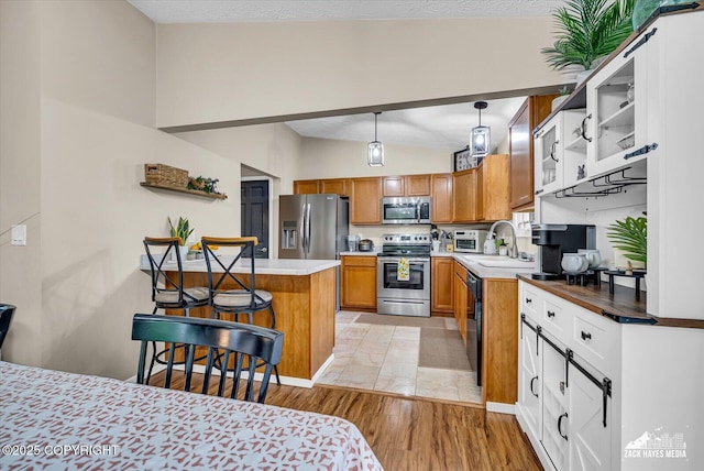 19705 Citation Rd, Eagle River, AK 99577 - kitchen with appliances with stainless steel finishes, brown cabinets, open shelves, a breakfast bar area, and lofted ceiling