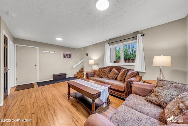 19705 Citation Rd, Eagle River, AK 99577 - living area featuring a textured ceiling, stairs, light wood-style flooring, and baseboards