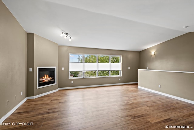 7616 Boundary Ave, Anchorage, AK 99504 - unfurnished living room featuring wood finished floors, a glass covered fireplace, and baseboards