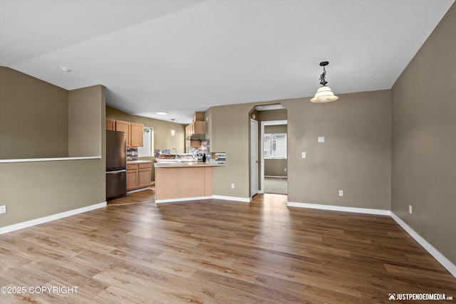 7616 Boundary Ave, Anchorage, AK 99504 - kitchen featuring freestanding refrigerator, open floor plan, arched walkways, wood finished floors, and a peninsula