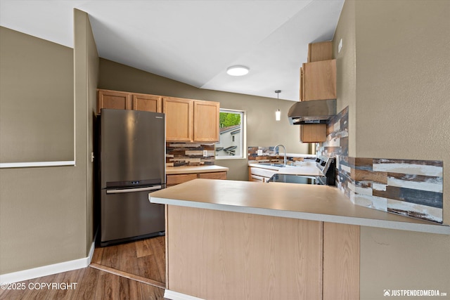 7616 Boundary Ave, Anchorage, AK 99504 - kitchen with freestanding refrigerator, a sink, a peninsula, wood finished floors, and stove